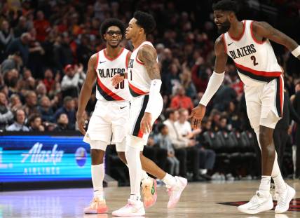Dec 19, 2023; Portland, Oregon, USA;  Portland Trail Blazers guard Scoot Henderson (00), left, and center Deandre Ayton (2) celebrates with guard Anfernee Simons (1) after Simons scored a basket to seal the 109-104 win over Phoenix Suns at Moda Center. Mandatory Credit: Jaime Valdez-USA TODAY Sports