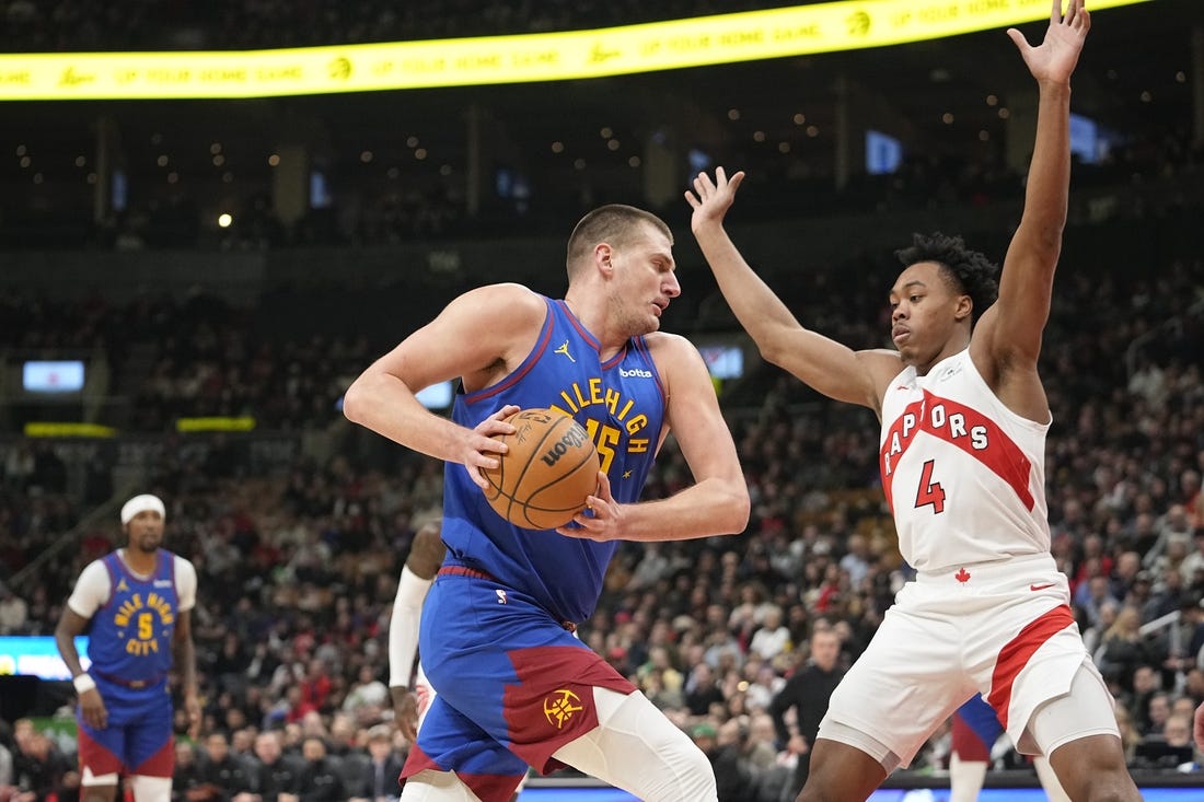 Dec 20, 2023; Toronto, Ontario, CAN; Denver Nuggets center Nikola Jokic (15) drives to the net against Toronto Raptors forward Scottie Barnes (4) during the first half at Scotiabank Arena. Mandatory Credit: John E. Sokolowski-USA TODAY Sports