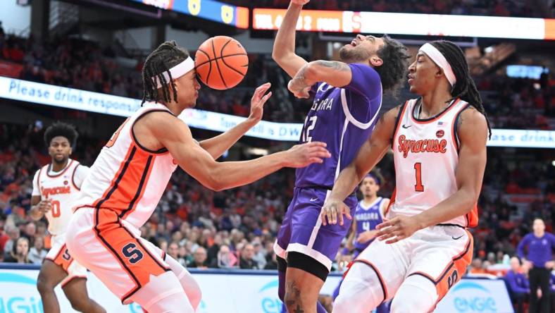 Dec 21, 2023; Syracuse, New York, USA; Syracuse Orange forward Benny Williams (13) has the ball hit his head on a drive by Niagara Purple Eagles guard Kwane Marble (12) with forward Maliq Brown (1) in the first half at the JMA Wireless Dome. Mandatory Credit: Mark Konezny-USA TODAY Sports