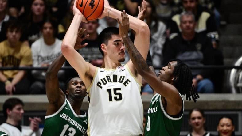 Dec 21, 2023; West Lafayette, Indiana, USA;  Purdue Boilermakers center Zach Edey (15) keeps the ball away from Jacksonville Dolphins guard Robert McCray V (13) and forward Stephon Payne III (0) right, during the first half at Mackey Arena. Mandatory Credit: Marc Lebryk-USA TODAY Sports