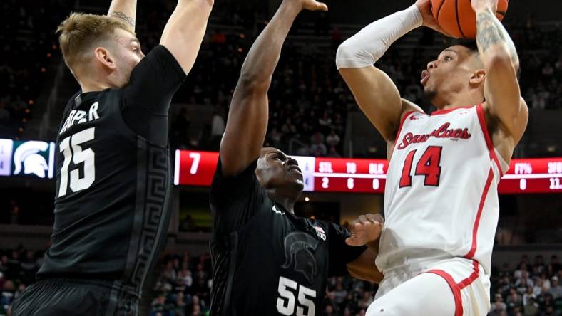 Dec 21, 2023; East Lansing, Michigan, USA; Stony Brook Seawolves guard Tyler Stephenson-Moore (14)can   t see an open shot past the defense of Michigan State Spartans forward Coen Carr (55) and Michigan State Spartans center Carson Cooper (15) at Jack Breslin Student Events Center. Mandatory Credit: Dale Young-USA TODAY Sports