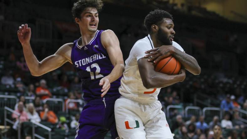 Dec 21, 2023; Coral Gables, Florida, USA; Miami Hurricanes guard Wooga Poplar (5) grabs a rebound against Stonehill Skyhawks guard Thatcher Stone (12) during the first half at Watsco Center. Mandatory Credit: Sam Navarro-USA TODAY Sports