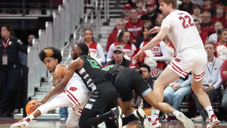 Dec 22, 2023; Madison, Wisconsin, USA; Wisconsin Badgers guard Chucky Hepburn (23) reaches a loose ball before Chicago State Cougars guard Brent Davis (12) as Chicago State Cougars forward Noble Crawford (15) and Wisconsin Badgers forward Steven Crowl (22) look on during the first half at the Kohl Center. Mandatory Credit: Kayla Wolf-USA TODAY Sports