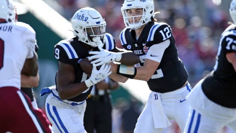 Dec 23, 2023; Birmingham, AL, USA; Duke Blue Devils quarterback Grayson Loftis (12) hands the ball off to Duke Blue Devils running back Jaquez Moore (9) during the first half against the Troy Trojans at Protective Stadium. Mandatory Credit: Petre Thomas-USA TODAY Sports