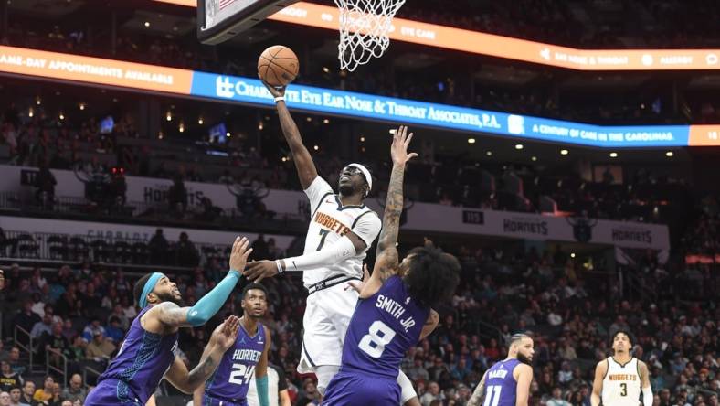 Dec 23, 2023; Charlotte, North Carolina, USA;  Denver Nuggets guard Reggie Jackson (7) drives against Charlotte Hornets forward Miles Bridges (0) and guard Nick Smith Jr. (8) during the first half at the Spectrum Center. Mandatory Credit: Sam Sharpe-USA TODAY Sports