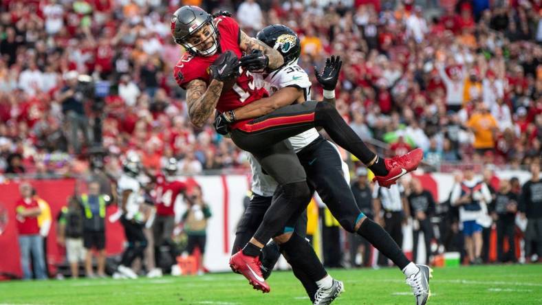 Dec 24, 2023; Tampa, Florida, USA; Tampa Bay Buccaneers wide receiver Mike Evans (13) makes the catch against Jacksonville Jaguars cornerback Tyson Campbell (32) in the second quarter for the touchdown at Raymond James Stadium. Mandatory Credit: Jeremy Reper-USA TODAY Sports