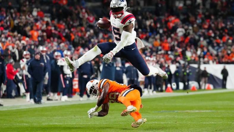 Dec 24, 2023; Denver, Colorado, USA; New England Patriots running back Ezekiel Elliott (15) jumps over Denver Broncos cornerback Ja'Quan McMillian (29) in the third quarter at Empower Field at Mile High. Mandatory Credit: Ron Chenoy-USA TODAY Sports