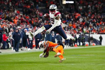 Dec 24, 2023; Denver, Colorado, USA; New England Patriots running back Ezekiel Elliott (15) jumps over Denver Broncos cornerback Ja'Quan McMillian (29) in the third quarter at Empower Field at Mile High. Mandatory Credit: Ron Chenoy-USA TODAY Sports