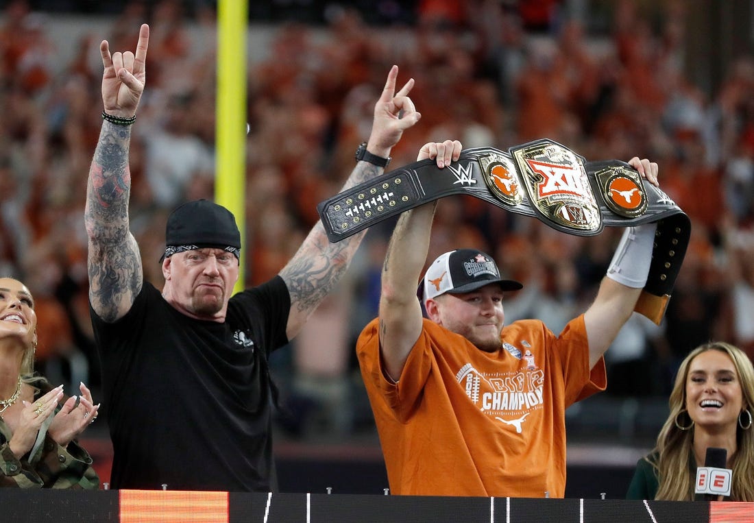 Texas's Quinn Ewers (3) holds up the WWE Big 12 Championship belt next to The Undertaker following the Big 12 Football Championship game between the Oklahoma State University Cowboys and the Texas Longhorns at the AT&T Stadium in Arlington, Texas, Saturday, Dec. 2, 2023.