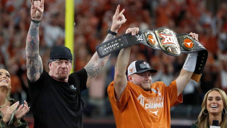 Texas's Quinn Ewers (3) holds up the WWE Big 12 Championship belt next to The Undertaker following the Big 12 Football Championship game between the Oklahoma State University Cowboys and the Texas Longhorns at the AT&T Stadium in Arlington, Texas, Saturday, Dec. 2, 2023.