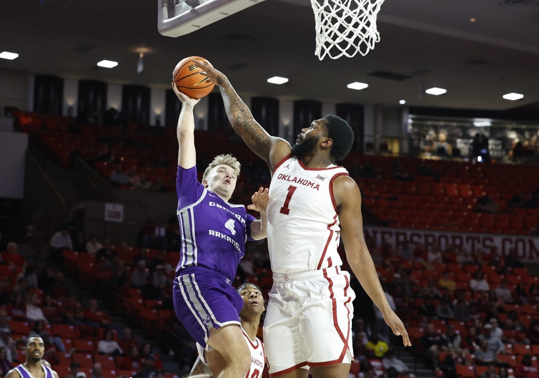 Dec 28, 2023; Norman, Oklahoma, USA; Central Arkansas Bears guard Johannes Kirsipuu (4) shoots as Oklahoma Sooners forward John Hugley IV (1) defends during the first half at Lloyd Noble Center. Mandatory Credit: Alonzo Adams-USA TODAY Sports