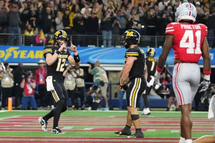 Dec 29, 2023; Arlington, Texas, USA; Missouri Tigers quarterback Brady Cook (12) pretends to take a photo of running back Cody Schrader (7) after he scored a touchdown during the third quarter of the Goodyear Cotton Bowl Classic against the Ohio State Buckeyes at AT&T Stadium. Ohio State lost 14-3.