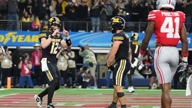 Dec 29, 2023; Arlington, Texas, USA; Missouri Tigers quarterback Brady Cook (12) pretends to take a photo of running back Cody Schrader (7) after he scored a touchdown during the third quarter of the Goodyear Cotton Bowl Classic against the Ohio State Buckeyes at AT&T Stadium. Ohio State lost 14-3.