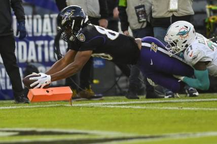 Dec 31, 2023; Baltimore, Maryland, USA;  Baltimore Ravens tight end Isaiah Likely (80) dives for a touchdown  as Miami Dolphins safety DeShon Elliott (21) defends during the first half at M&T Bank Stadium. Mandatory Credit: Tommy Gilligan-USA TODAY Sports