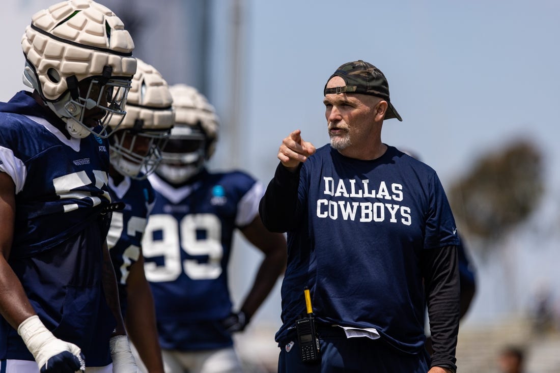 Aug 4, 2022; Oxnard, CA, USA; Dallas Cowboys defensive coordinator Dan Quinn talks to players during training camp at River Ridge Playing Fields in Oxnard, California. Mandatory Credit: Jason Parkhurst-USA TODAY Sports