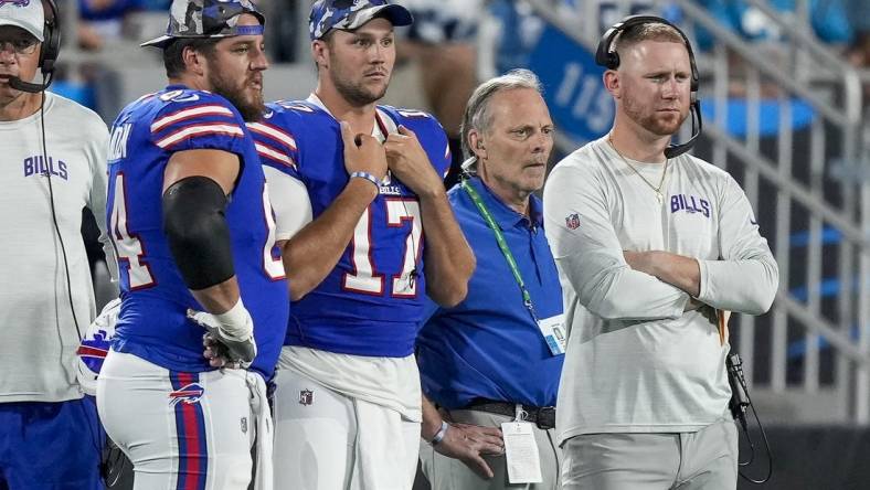 Aug 26, 2022; Charlotte, North Carolina, USA; Buffalo Bills guard Greg Van Roten (64), quarterback Josh Allen (17) and offensive coach Joe Brady watch as Carolina Panthers quarterback Sam Darnold (not pictured) is carted off the field during the second half at Bank of America Stadium. Mandatory Credit: Jim Dedmon-USA TODAY Sports