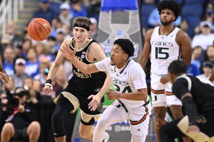 Mar 9, 2023; Greensboro, NC, USA; Miami (Fl) Hurricanes guard Nijel Pack (24) with the ball as Wake Forest Demon Deacons forward Andrew Carr (11) defends during the second half of the quarterfinals of the ACC tournament at Greensboro Coliseum. Mandatory Credit: Bob Donnan-USA TODAY Sports