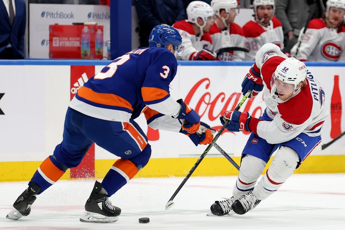 Apr 12, 2023; Elmont, New York, USA; Montreal Canadiens center Rem Pitlick (32) and New York Islanders defenseman Adam Pelech (3) fight for the puck during the first period at UBS Arena. Mandatory Credit: Brad Penner-USA TODAY Sports