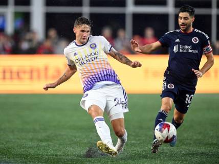 Jun 17, 2023; Foxborough, Massachusetts, USA; Orlando City defender Michael Halliday (26) passes the ball in front of New England Revolution midfielder Carles Gil (10) during the first half of a match at Gillette Stadium. Mandatory Credit: Brian Fluharty-USA TODAY Sports