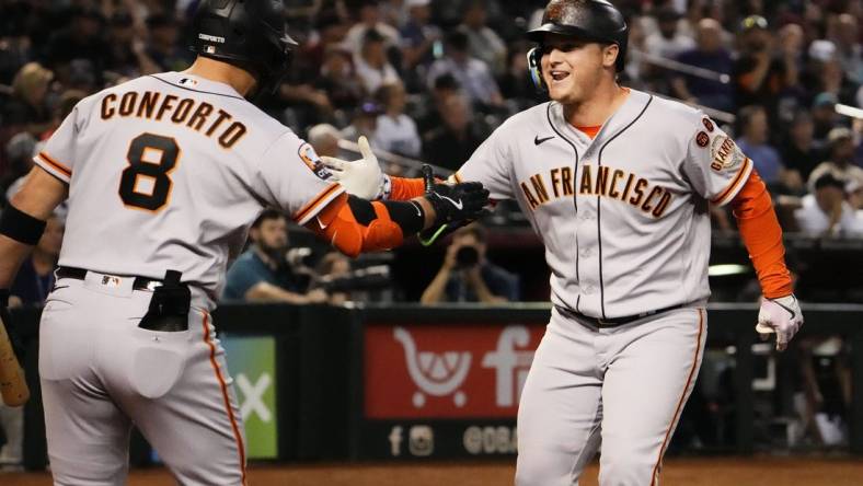 San Francisco Giants designated hitter Joc Pederson (right) reacts after hitting a home run off of Arizona Diamondbacks starting pitcher Zac Gallen (23) in the first inning at Chase Field in Phoenix on Sept. 19, 2023.