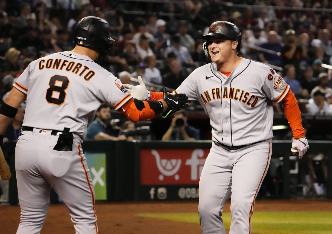 San Francisco Giants designated hitter Joc Pederson (right) reacts after hitting a home run off of Arizona Diamondbacks starting pitcher Zac Gallen (23) in the first inning at Chase Field in Phoenix on Sept. 19, 2023.