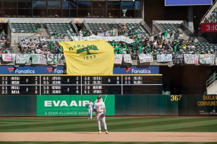 Sep 24, 2023; Oakland, California, USA; Fans in the outfield bleachers display homemade signs critical of the MLB Commissioner and Oakland Athletics ownership and Oakland Athletics infielder Zack Gelof (20) and outfielder Brent Rooker (25) stand on the field during the eighth inning against the Detroit Tigers at Oakland-Alameda County Coliseum. Mandatory Credit: Robert Edwards-USA TODAY Sports