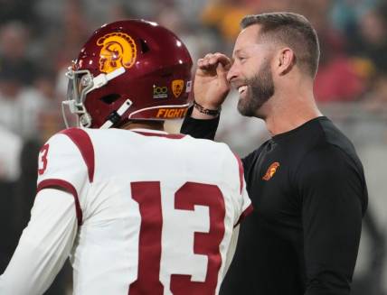 The former Arizona Cardinals head coach, now an assistant coach with the USC Trojans, Kliff Kingsbury talks to quarterback Caleb Williams (13) during the pregame warmup before playing the Arizona State Sun Devils at Mountain America Stadium in Tempe on Sept. 23, 2023.