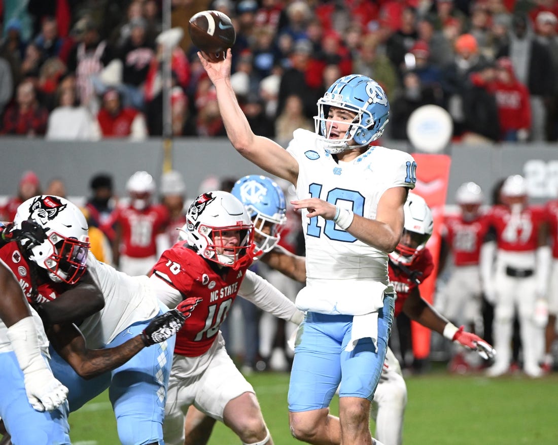 Nov 25, 2023; Raleigh, North Carolina, USA; North Carolina Tar Heels quarterback Drake Maye (10) throws a pass against North Carolina State Wolfpack linebacker Caden Fordham during the first half at Carter-Finley Stadium. Mandatory Credit: Rob Kinnan-USA TODAY Sports