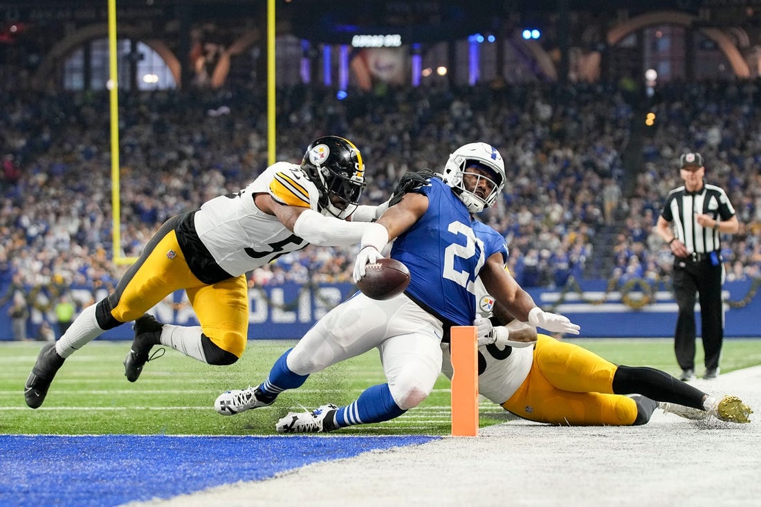 Indianapolis Colts running back Zack Moss (21) slides into the end zone for a touchdown while being chased by Pittsburgh Steelers linebacker Elandon Roberts (50) and Pittsburgh Steelers linebacker Mykal Walker (38) on Saturday, Dec. 16, 2023, during a game against the Pittsburgh Steelers at Lucas Oil Stadium in Indianapolis.