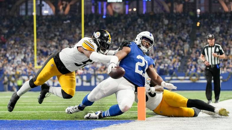 Indianapolis Colts running back Zack Moss (21) slides into the end zone for a touchdown while being chased by Pittsburgh Steelers linebacker Elandon Roberts (50) and Pittsburgh Steelers linebacker Mykal Walker (38) on Saturday, Dec. 16, 2023, during a game against the Pittsburgh Steelers at Lucas Oil Stadium in Indianapolis.