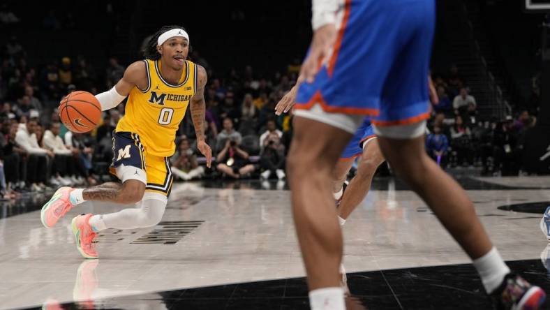 Dec 19, 2023; Charlotte, North Carolina, USA; Michigan Wolverines guard Dug McDaniel (0) drives to the basket against the Florida Gators during the first half at Spectrum Center. Mandatory Credit: Jim Dedmon-USA TODAY Sports