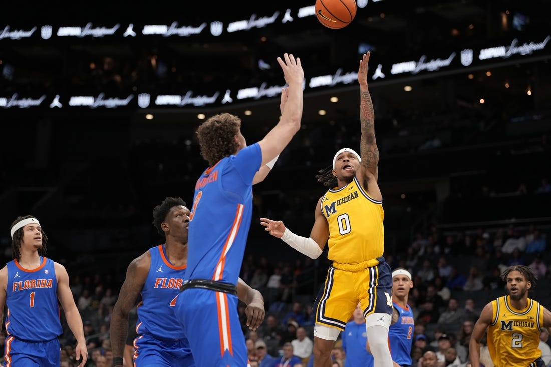 Dec 19, 2023; Charlotte, North Carolina, USA; Michigan Wolverines guard Dug McDaniel (0) goes up for a shot defended by Florida Gators center Micah Handlogten (3) during the first half at Spectrum Center. Mandatory Credit: Jim Dedmon-USA TODAY Sports