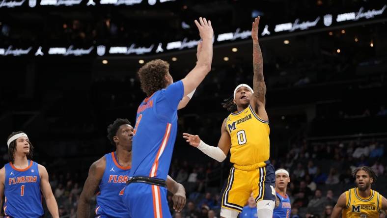 Dec 19, 2023; Charlotte, North Carolina, USA; Michigan Wolverines guard Dug McDaniel (0) goes up for a shot defended by Florida Gators center Micah Handlogten (3) during the first half at Spectrum Center. Mandatory Credit: Jim Dedmon-USA TODAY Sports