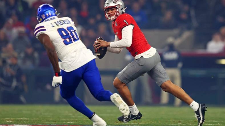 Dec 26, 2023; Phoenix, AZ, USA; UNLV Rebels quarterback Jayden Maiava (1) roles out to pass against Kansas Jayhawks defensive lineman Jereme Robinson (90) during the first quarter in the Guaranteed Rate Bowl at Chase Field. Mandatory Credit: Mark J. Rebilas-USA TODAY Sports