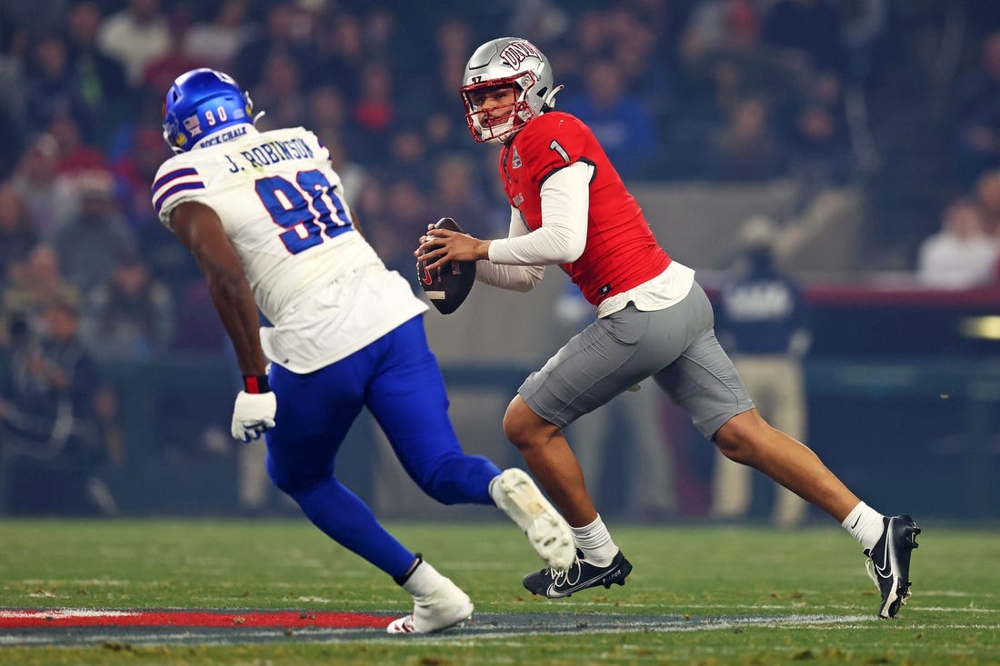 Dec 26, 2023; Phoenix, AZ, USA; UNLV Rebels quarterback Jayden Maiava (1) roles out to pass against Kansas Jayhawks defensive lineman Jereme Robinson (90) during the first quarter in the Guaranteed Rate Bowl at Chase Field. Mandatory Credit: Mark J. Rebilas-USA TODAY Sports