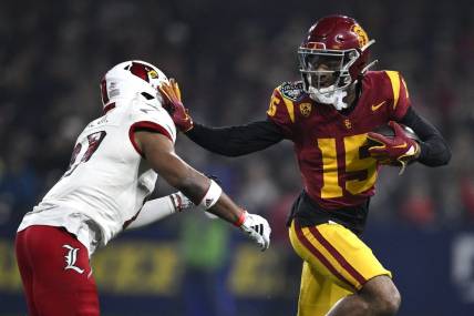 Dec 27, 2023; San Diego, CA, USA; USC Trojans wide receiver Dorian Singer (15) stiff arms Louisville Cardinals defensive back Devin Neal (27) during the first half at Petco Park. Mandatory Credit: Orlando Ramirez-USA TODAY Sports