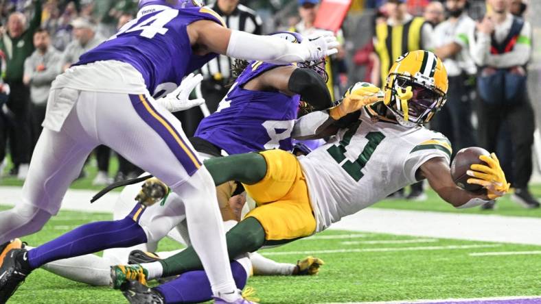 Dec 31, 2023; Minneapolis, Minnesota, USA; Green Bay Packers wide receiver Jayden Reed (11) scores a touchdown  as Minnesota Vikings safety Josh Metellus and safety Camryn Bynum (24) attempt to make the tackle during the second quarter at U.S. Bank Stadium. Mandatory Credit: Jeffrey Becker-USA TODAY Sports