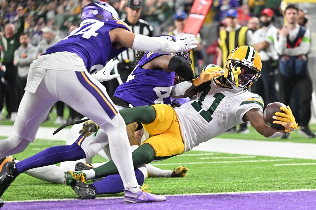 Dec 31, 2023; Minneapolis, Minnesota, USA; Green Bay Packers wide receiver Jayden Reed (11) scores a touchdown  as Minnesota Vikings safety Josh Metellus and safety Camryn Bynum (24) attempt to make the tackle during the second quarter at U.S. Bank Stadium. Mandatory Credit: Jeffrey Becker-USA TODAY Sports
