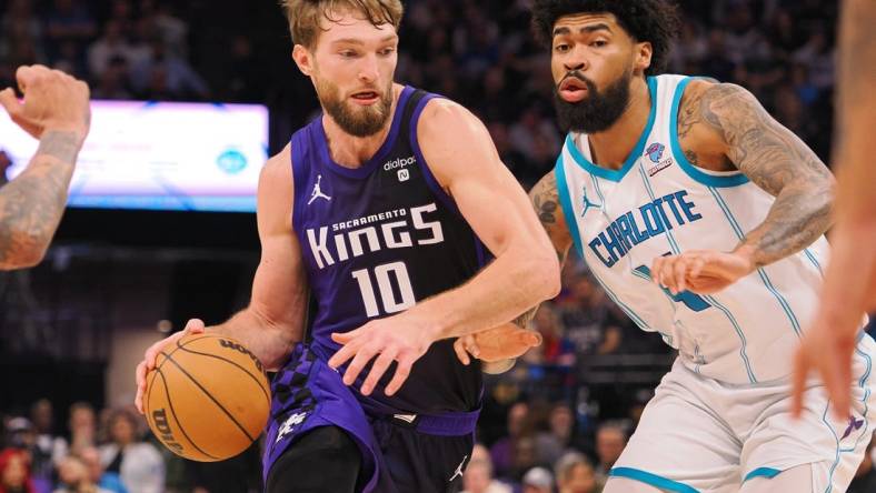 Jan 2, 2024; Sacramento, California, USA; Sacramento Kings center Domantas Sabonis (10) controls the ball against Charlotte Hornets center Nick Richards (4) during the second quarter at Golden 1 Center. Mandatory Credit: Kelley L Cox-USA TODAY Sports