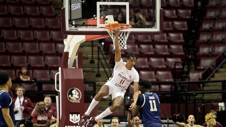 Jan 3, 2024; Tallahassee, Florida, USA; Florida State Seminoles forward Baba Miller (11) hangs on the rim after a dunk during the first half against the Georgia Tech Yellow Jackets at Donald L. Tucker Center. Mandatory Credit: Melina Myers-USA TODAY Sports