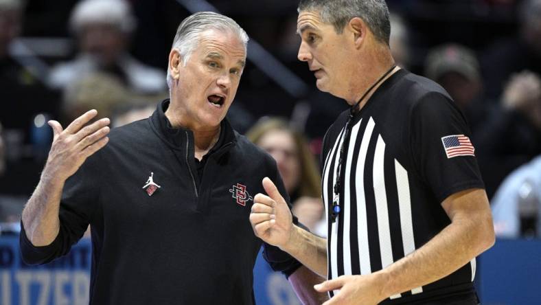 Jan 6, 2024; San Diego, California, USA; San Diego State Aztecs head coach Brian Dutcher (left) speaks with referee Michael Reed during the second half against the UNLV Rebels at Viejas Arena. Mandatory Credit: Orlando Ramirez-USA TODAY Sports