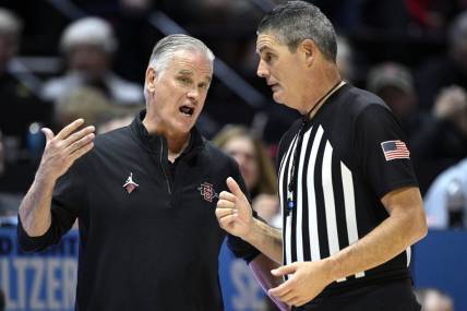 Jan 6, 2024; San Diego, California, USA; San Diego State Aztecs head coach Brian Dutcher (left) speaks with referee Michael Reed during the second half against the UNLV Rebels at Viejas Arena. Mandatory Credit: Orlando Ramirez-USA TODAY Sports