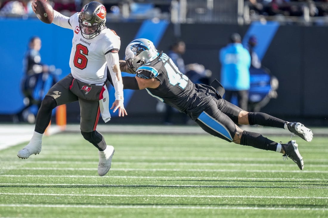 Jan 7, 2024; Charlotte, North Carolina, USA; Tampa Bay Buccaneers quarterback Baker Mayfield (6) avoids the tackle by Carolina Panthers linebacker Frankie Luvu (49) during the second half at Bank of America Stadium. Mandatory Credit: Jim Dedmon-USA TODAY Sports