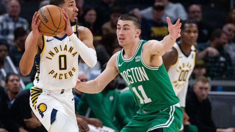 Jan 8, 2024; Indianapolis, Indiana, USA; Indiana Pacers guard Tyrese Haliburton (0) looks to pass the ball while Boston Celtics guard Payton Pritchard (11) defends in the first half at Gainbridge Fieldhouse. Mandatory Credit: Trevor Ruszkowski-USA TODAY Sports