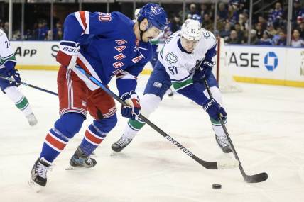 Jan 8, 2024; New York, New York, USA;  New York Rangers left wing Chris Kreider (20) and Vancouver Canucks defenseman Tyler Myers (57) battle for control of the puck in the first period at Madison Square Garden. Mandatory Credit: Wendell Cruz-USA TODAY Sports