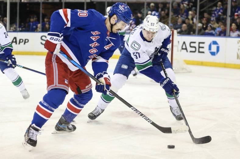 Jan 8, 2024; New York, New York, USA;  New York Rangers left wing Chris Kreider (20) and Vancouver Canucks defenseman Tyler Myers (57) battle for control of the puck in the first period at Madison Square Garden. Mandatory Credit: Wendell Cruz-USA TODAY Sports
