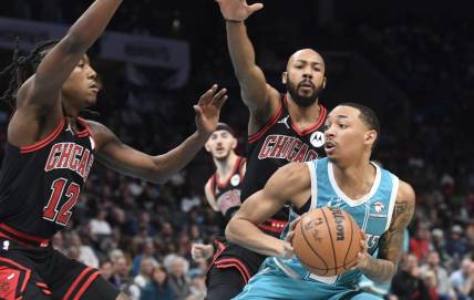 Jan 8, 2024; Charlotte, North Carolina, USA;  Charlotte Hornets guard Nick Smith Jr. (8) looks to shoot as he is defended by Chicago Bulls guard Aye Dosunmu (12) and guard Jevon Carter (5) during the first half at the Spectrum Center. Mandatory Credit: Sam Sharpe-USA TODAY Sports