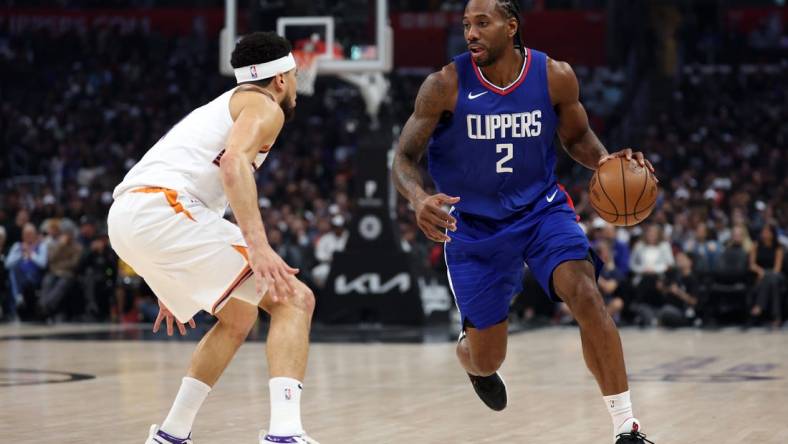 Jan 8, 2024; Los Angeles, California, USA;  Los Angeles Clippers forward Kawhi Leonard (2) dribbles the ball against Phoenix Suns guard Devin Booker (1) during the first quarter at Crypto.com Arena. Mandatory Credit: Kiyoshi Mio-USA TODAY Sports