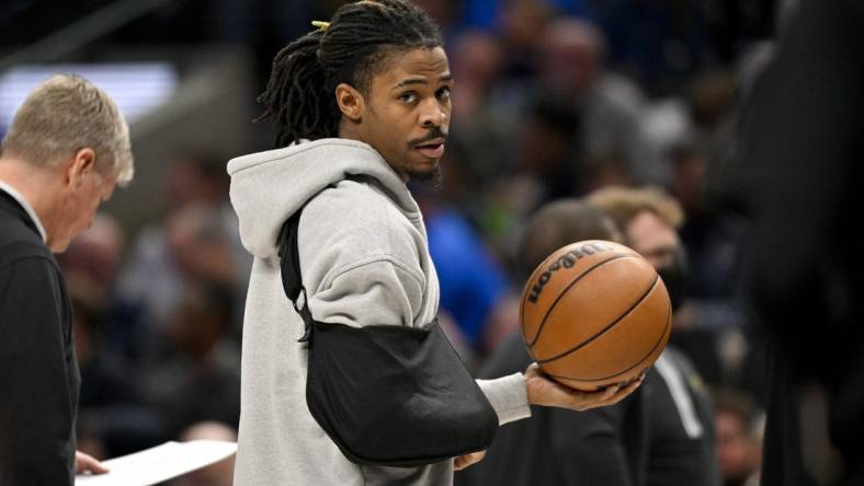 Jan 9, 2024; Dallas, Texas, USA; Memphis Grizzlies guard Ja Morant (12) looks on while wearing his arm in a sling during a time stoppage in the first quarter of the game between the Dallas Mavericks and the Memphis Grizzlies at the American Airlines Center. Mandatory Credit: Jerome Miron-USA TODAY Sports