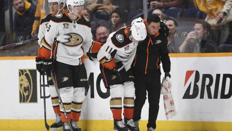 Jan 9, 2024; Nashville, Tennessee, USA; Anaheim Ducks center Trevor Zegras (11) is helped off the ice after an injury first period against the Nashville Predators at Bridgestone Arena. Mandatory Credit: Christopher Hanewinckel-USA TODAY Sports